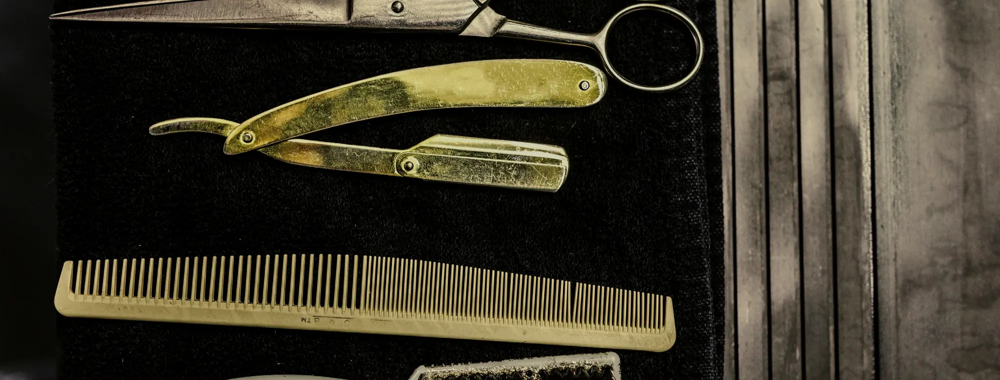 Rasoir doré, ciseaux et peigne posés sur une serviette noire